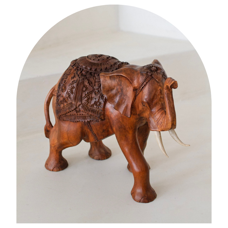 Wooden elephant sculpture with intricate carvings on a white background