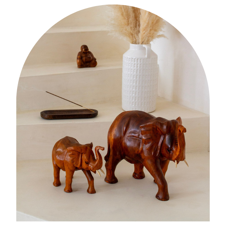Wooden elephant sculptures on a shelf with a white vase and incense stick.