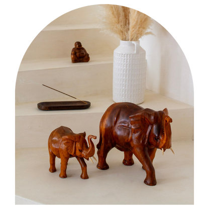 Wooden elephant sculptures on a shelf with a white vase and incense stick.