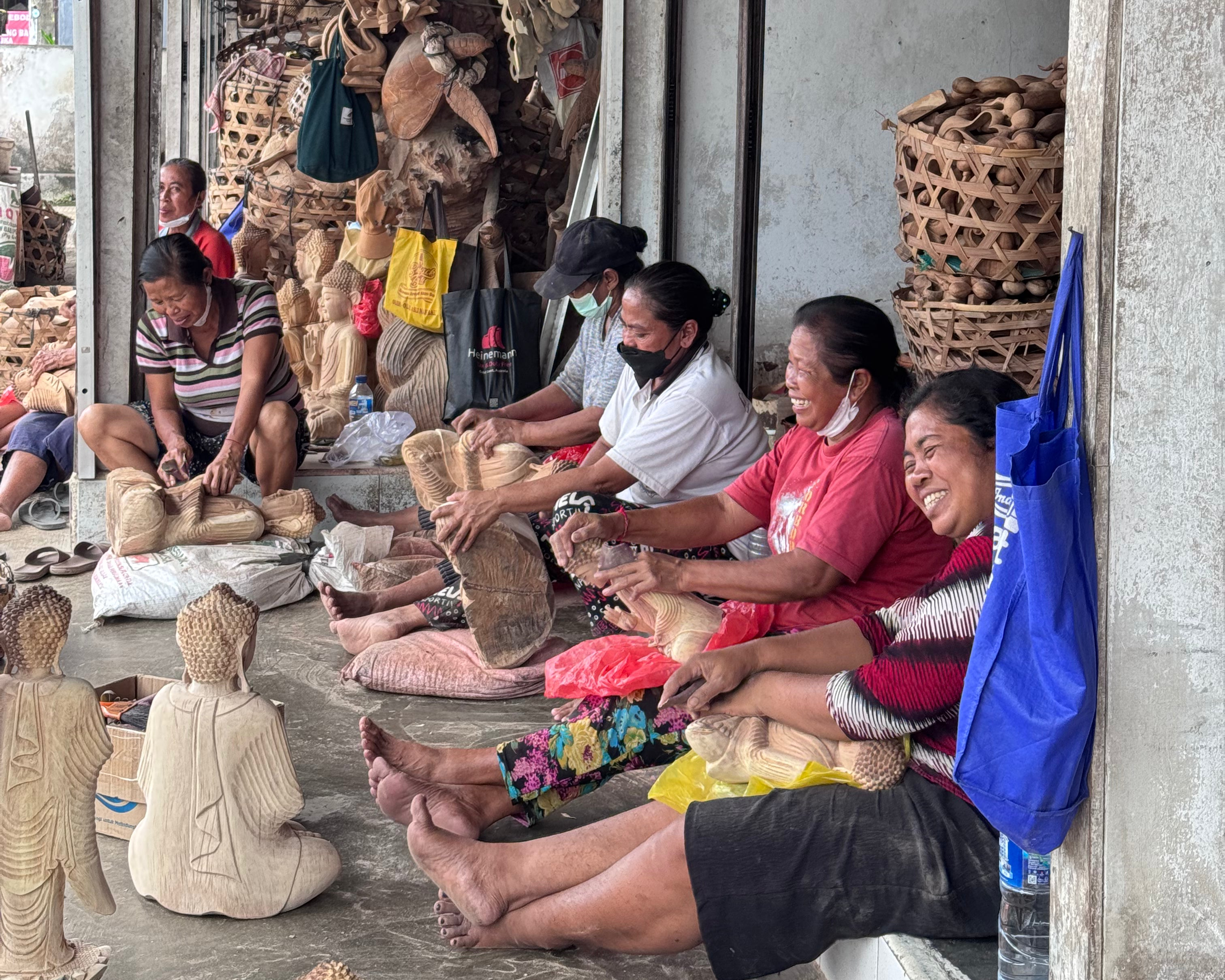 People sitting on the ground making handcrafts in a workshop.