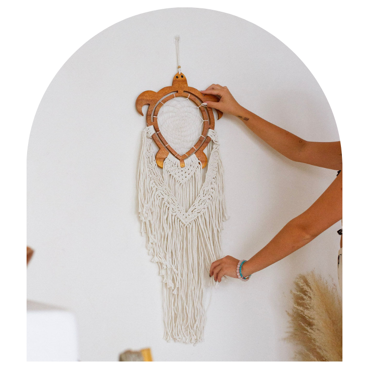 Handmade wall hanging with wooden frame and white strings on a plain background