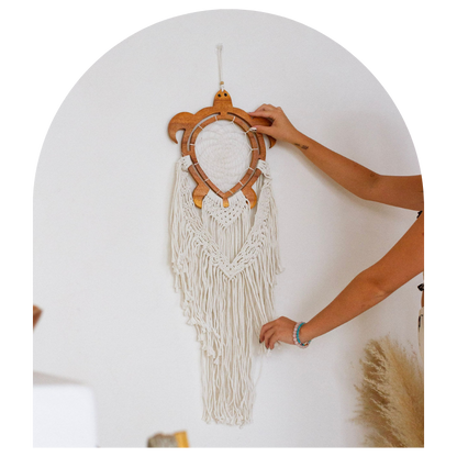 Handmade wall hanging with wooden frame and white strings on a plain background